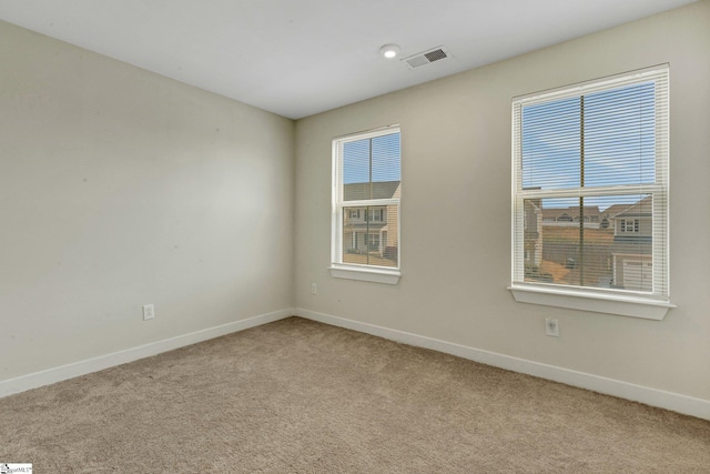 spare room featuring baseboards, visible vents, plenty of natural light, and light colored carpet