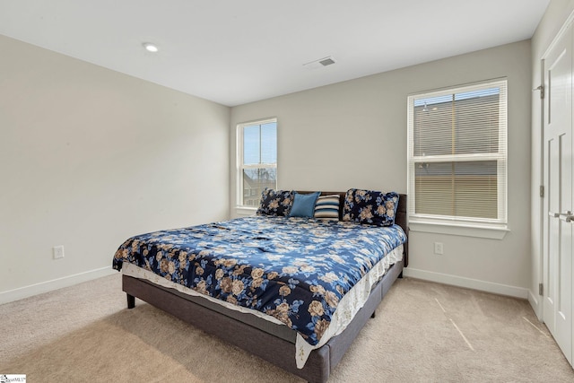 bedroom with baseboards, visible vents, and light colored carpet
