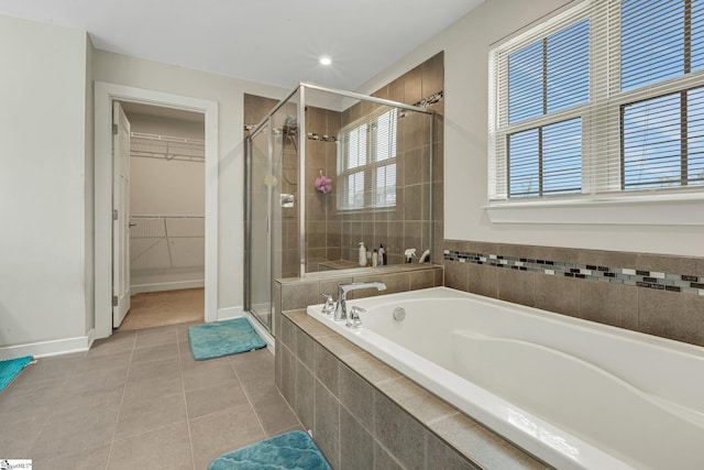 full bathroom with a spacious closet, baseboards, a shower stall, tile patterned floors, and a bath
