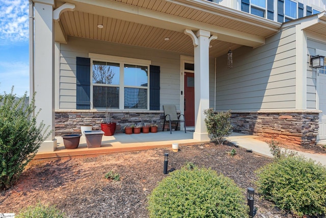 view of exterior entry with stone siding and covered porch