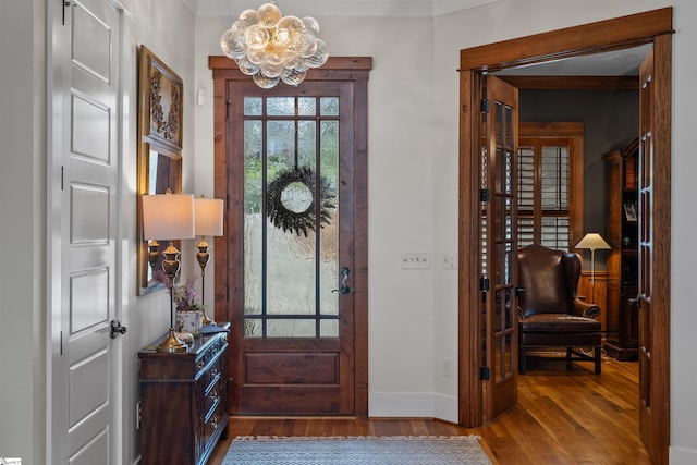 entrance foyer with baseboards, wood finished floors, and a notable chandelier