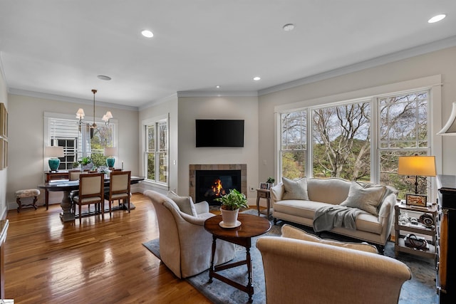 living room featuring recessed lighting, a tile fireplace, crown molding, and wood finished floors
