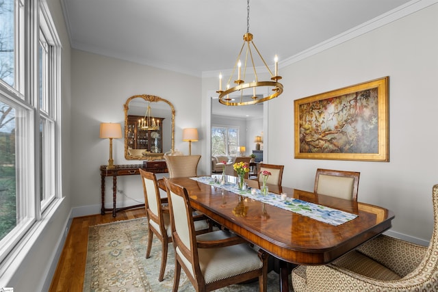 dining space with baseboards, a notable chandelier, wood finished floors, and ornamental molding