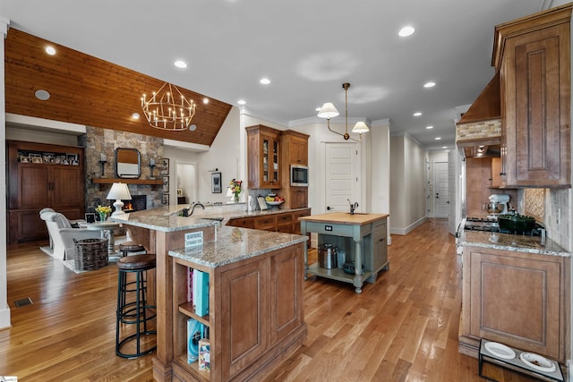 kitchen with open shelves, stainless steel microwave, decorative backsplash, wooden counters, and custom exhaust hood