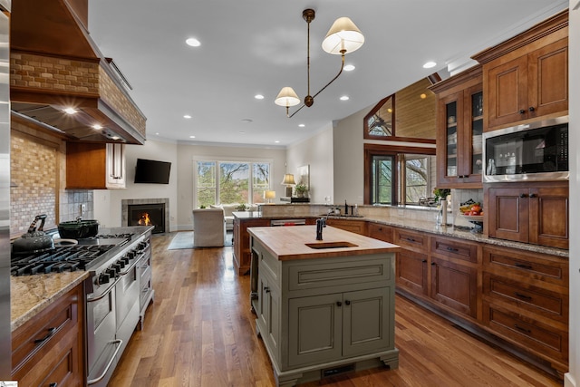 kitchen with range with two ovens, tasteful backsplash, wood finished floors, open floor plan, and butcher block counters