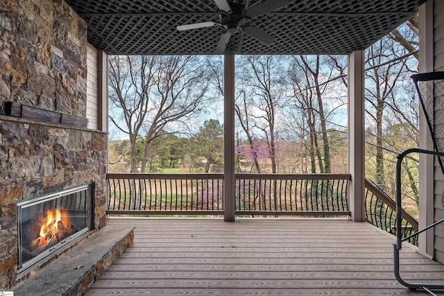 wooden terrace with an outdoor stone fireplace and ceiling fan