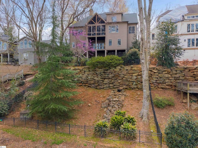 back of house with a chimney and fence