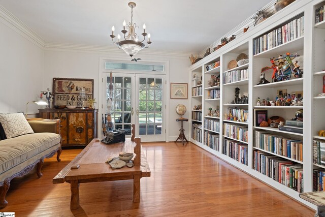 sitting room featuring a notable chandelier, crown molding, and wood finished floors