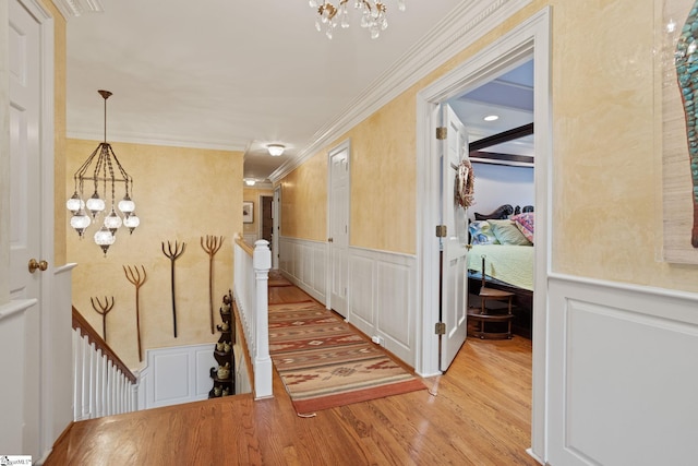 hallway featuring a decorative wall, wood finished floors, and an inviting chandelier