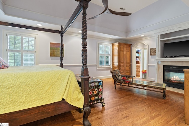 bedroom with multiple windows, visible vents, wood finished floors, and ornamental molding