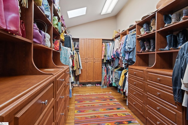 spacious closet with lofted ceiling with skylight and light wood-type flooring