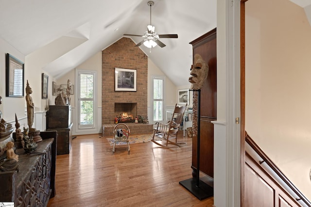 living room with a fireplace, wood finished floors, vaulted ceiling, and ceiling fan