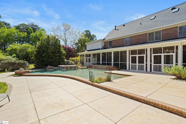 view of swimming pool with a pool with connected hot tub, a sunroom, and a patio