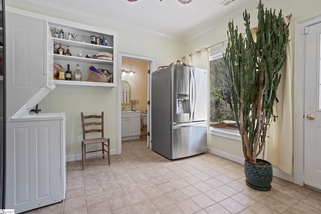 kitchen with stainless steel fridge, stacked washer and clothes dryer, open shelves, ornamental molding, and baseboards