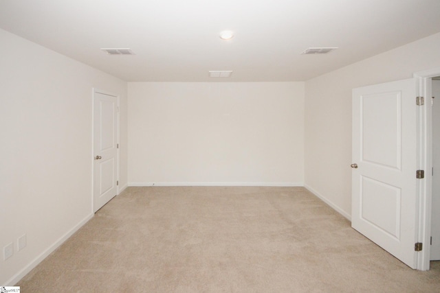 spare room with light carpet, visible vents, and baseboards