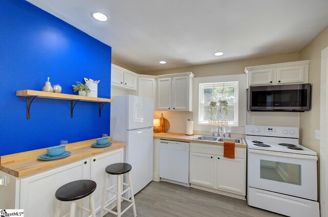 kitchen with light wood-type flooring, white appliances, a sink, wood counters, and white cabinets