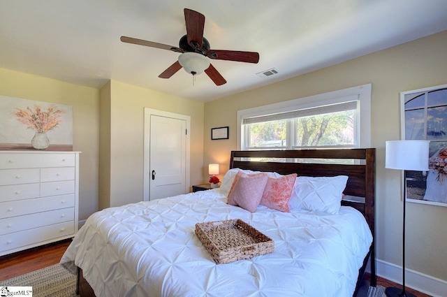 bedroom featuring baseboards, visible vents, wood finished floors, and ceiling fan