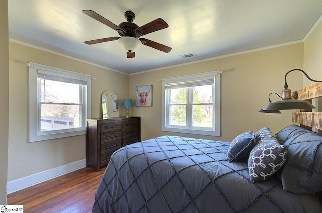 bedroom with multiple windows, visible vents, crown molding, and wood finished floors