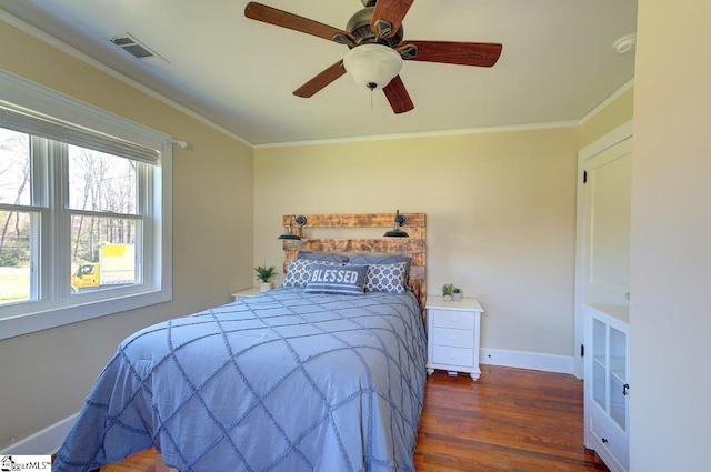bedroom featuring visible vents, baseboards, ornamental molding, wood finished floors, and a ceiling fan