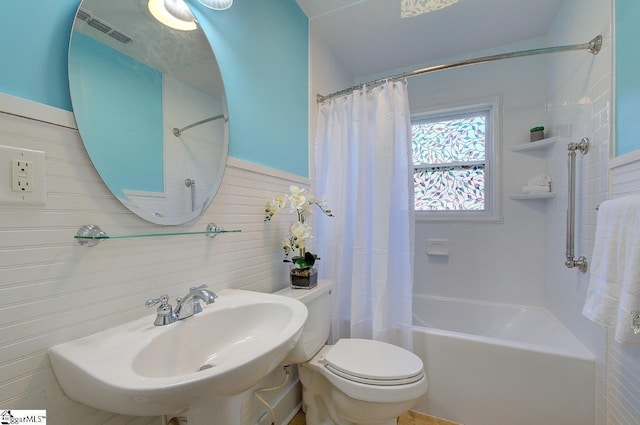 bathroom with tile walls, toilet, a sink, and shower / bath combo
