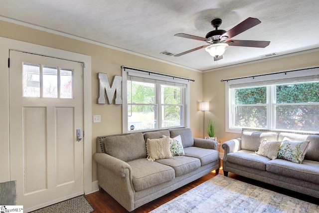 living room featuring a ceiling fan, ornamental molding, dark wood-type flooring, and a healthy amount of sunlight