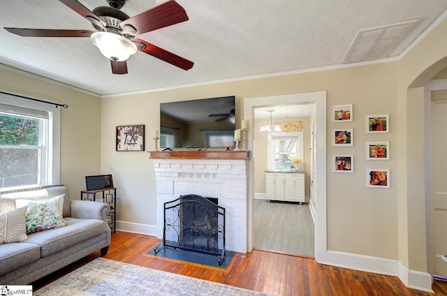 living area with arched walkways, ornamental molding, visible vents, and wood finished floors