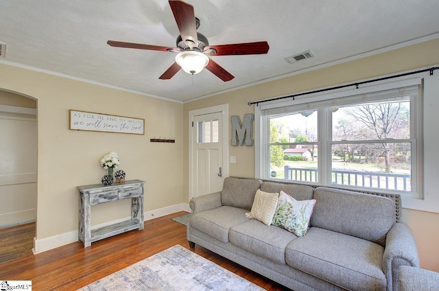 living room featuring visible vents, crown molding, ceiling fan, wood finished floors, and arched walkways