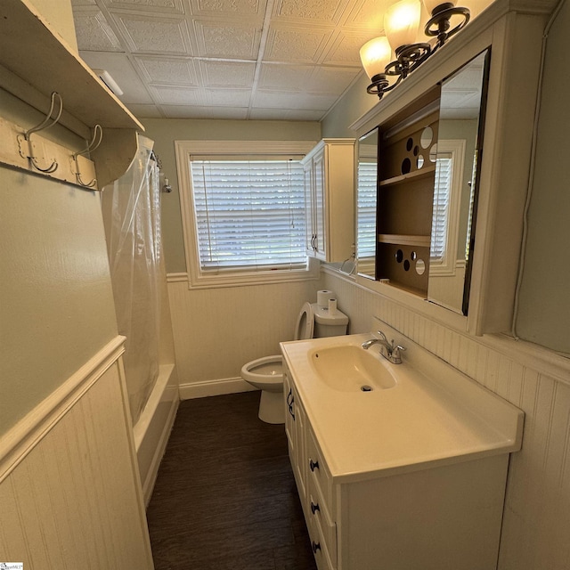 full bathroom featuring wood finished floors, toilet, an ornate ceiling, vanity, and wainscoting