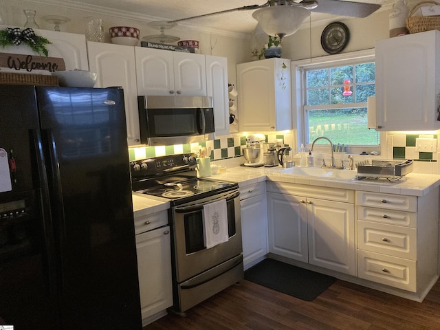 kitchen with a sink, white cabinetry, stainless steel appliances, tile countertops, and dark wood-style flooring