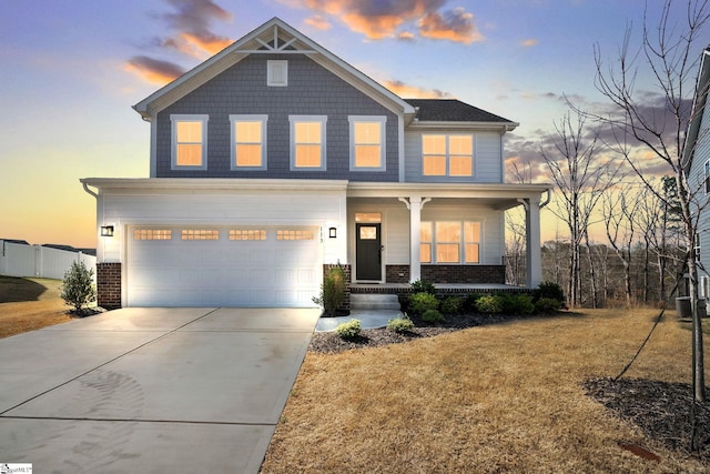 view of front facade with covered porch, a yard, brick siding, concrete driveway, and an attached garage