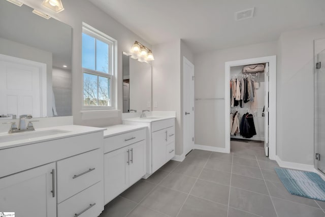bathroom with visible vents, tile patterned flooring, baseboards, a shower stall, and a sink