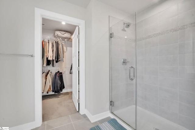 bathroom featuring tile patterned flooring, baseboards, a spacious closet, and a shower stall