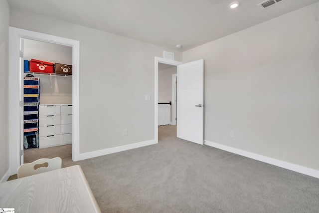unfurnished bedroom with baseboards, carpet flooring, a spacious closet, and visible vents