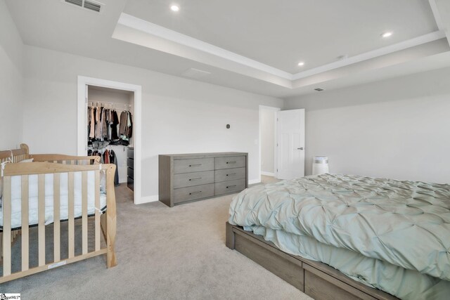 bedroom with a raised ceiling, carpet flooring, recessed lighting, and a walk in closet