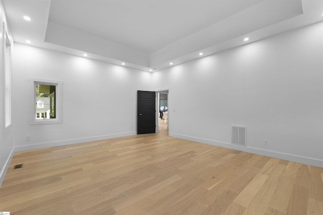 empty room with light wood finished floors, baseboards, and visible vents