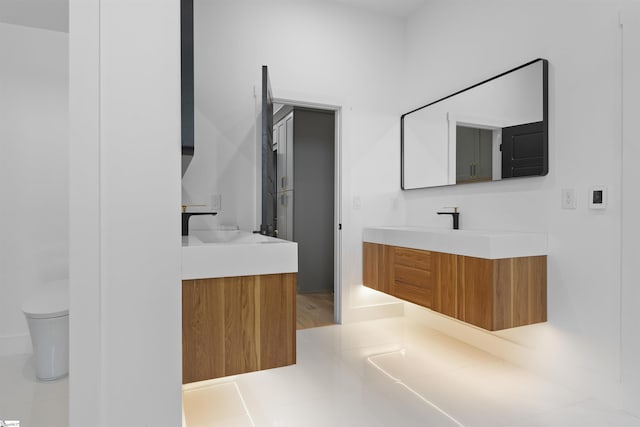bathroom featuring a sink, toilet, and two vanities