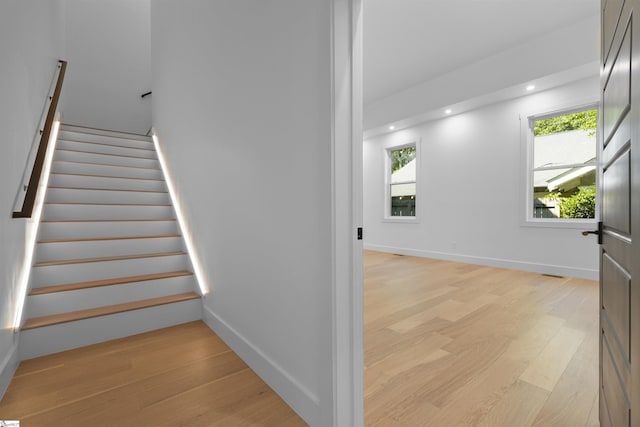 stairs featuring plenty of natural light, baseboards, and wood finished floors