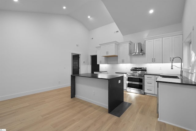 kitchen with range with two ovens, a sink, wall chimney exhaust hood, a center island, and dark countertops