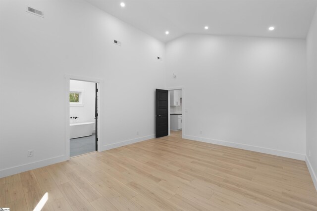unfurnished room with high vaulted ceiling, light wood finished floors, baseboards, visible vents, and recessed lighting