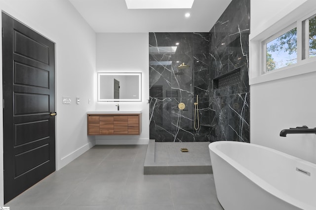 bathroom with vanity, a marble finish shower, baseboards, a skylight, and a freestanding bath