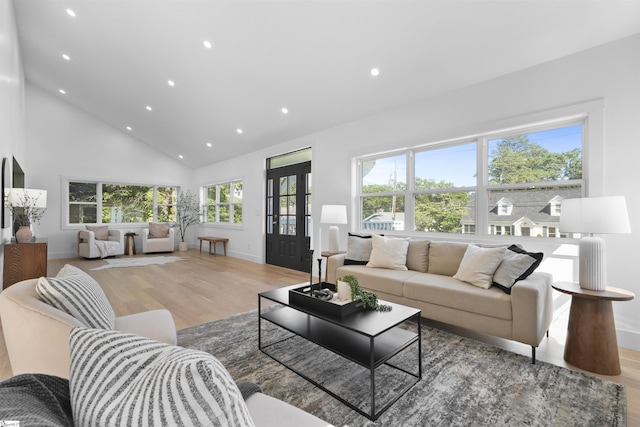 living area featuring baseboards, high vaulted ceiling, recessed lighting, and light wood-type flooring