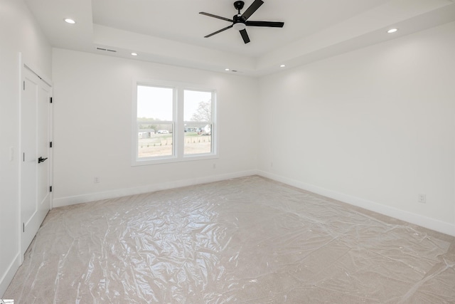 unfurnished room featuring baseboards, ceiling fan, recessed lighting, and a raised ceiling