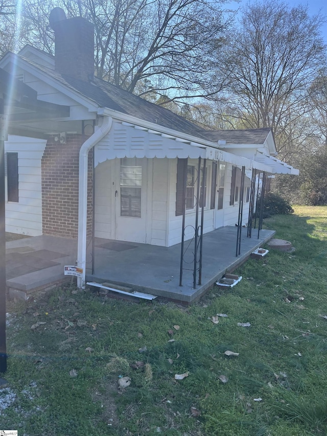 1273 Powerhouse Rd, Ware Shoals, SC 29692 - view of side of property featuring a lawn, brick siding, a chimney, and a patio