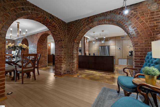 400 E Washington St Unit 28, Greenville, SC 29601 - interior space featuring visible vents, arched walkways, light wood-style floors, brick wall, and an inviting chandelier