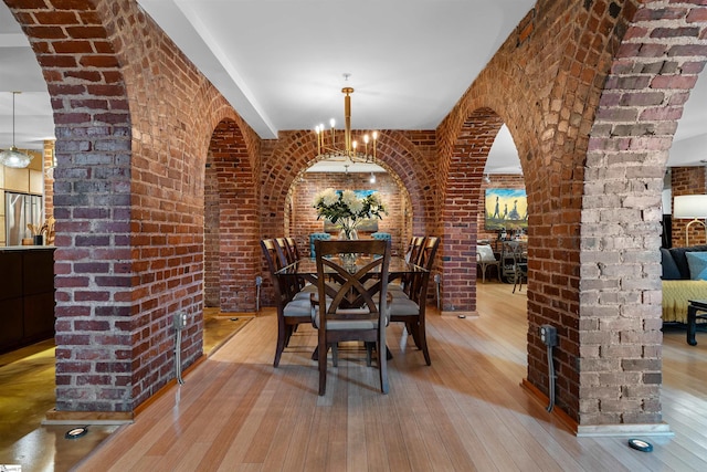 400 E Washington St Unit 28, Greenville, SC 29601 - unfurnished dining area with arched walkways, a chandelier, brick wall, and hardwood / wood-style flooring