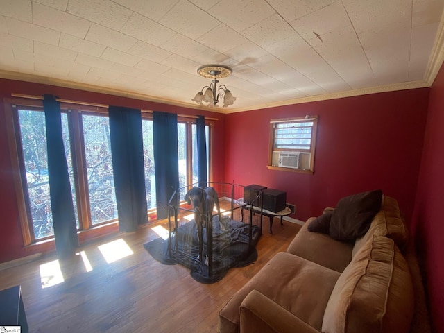 living area featuring ornamental molding, baseboards, a notable chandelier, and wood finished floors
