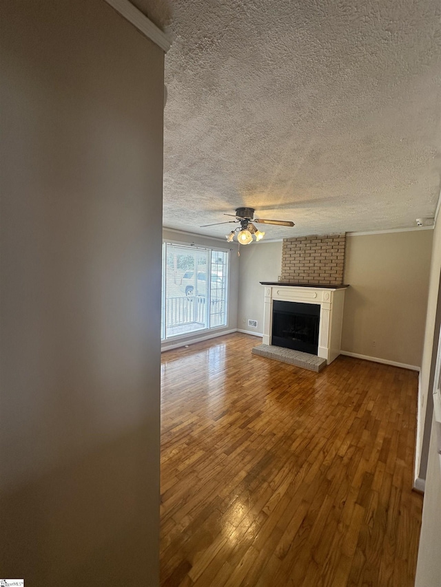 unfurnished living room with hardwood / wood-style floors, baseboards, a textured ceiling, ceiling fan, and a fireplace