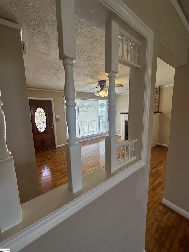 entrance foyer with crown molding, wood finished floors, ceiling fan, and a textured ceiling