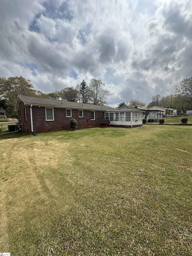 rear view of property with a lawn, a deck, and brick siding