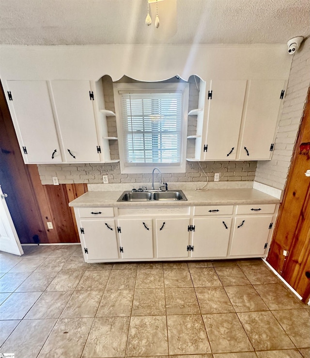 kitchen featuring white cabinetry, light countertops, a sink, and open shelves